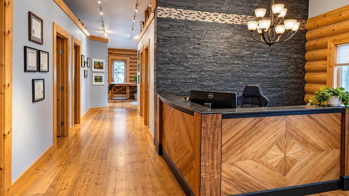 B-Well Physiotherapy reception area in Cochrane, Alberta, with warm wood finishes and a dark stone feature wall.